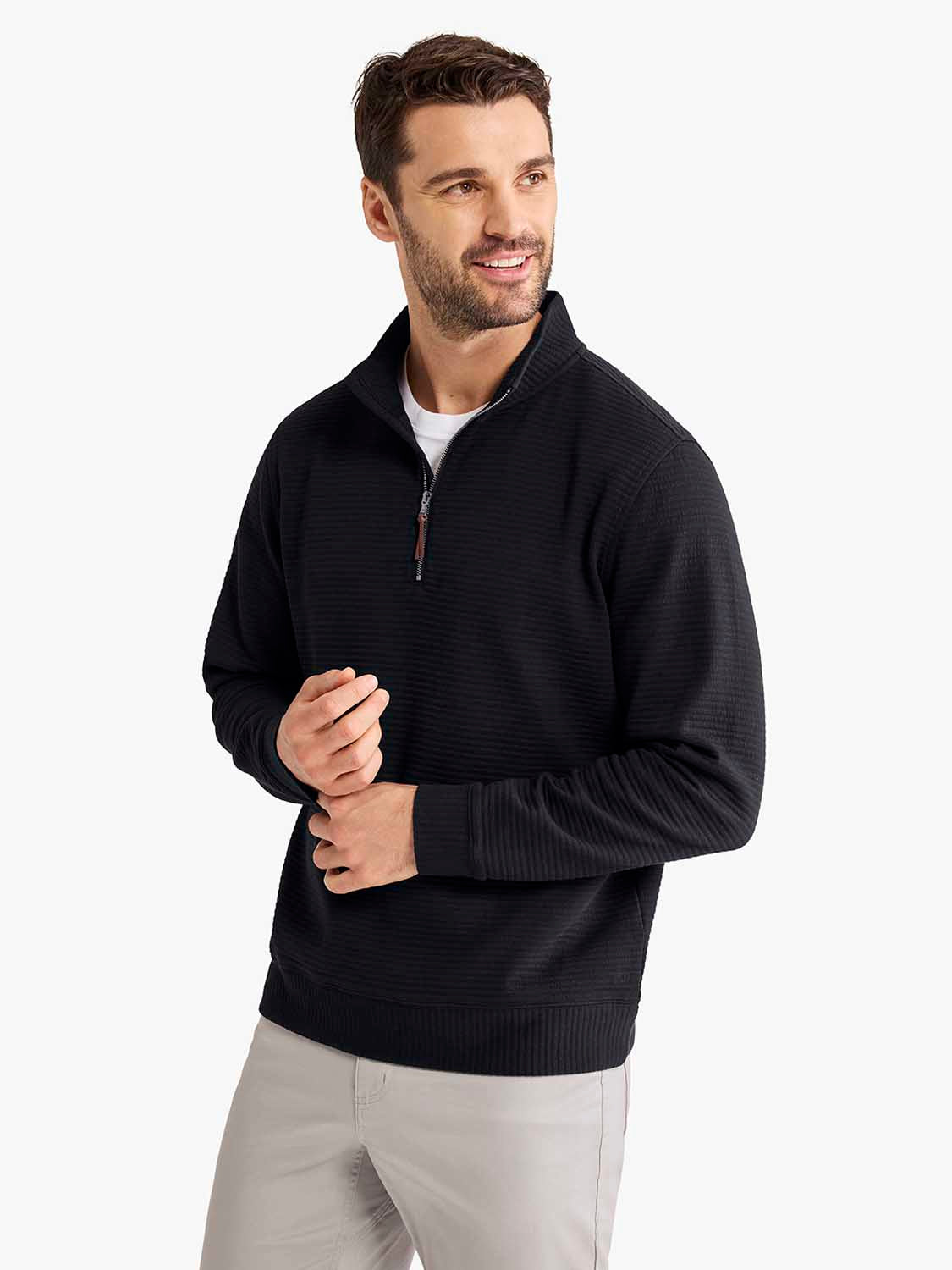 Man wearing a black quarter zip pullover with ribbed texture over a white shirt and light gray pants.