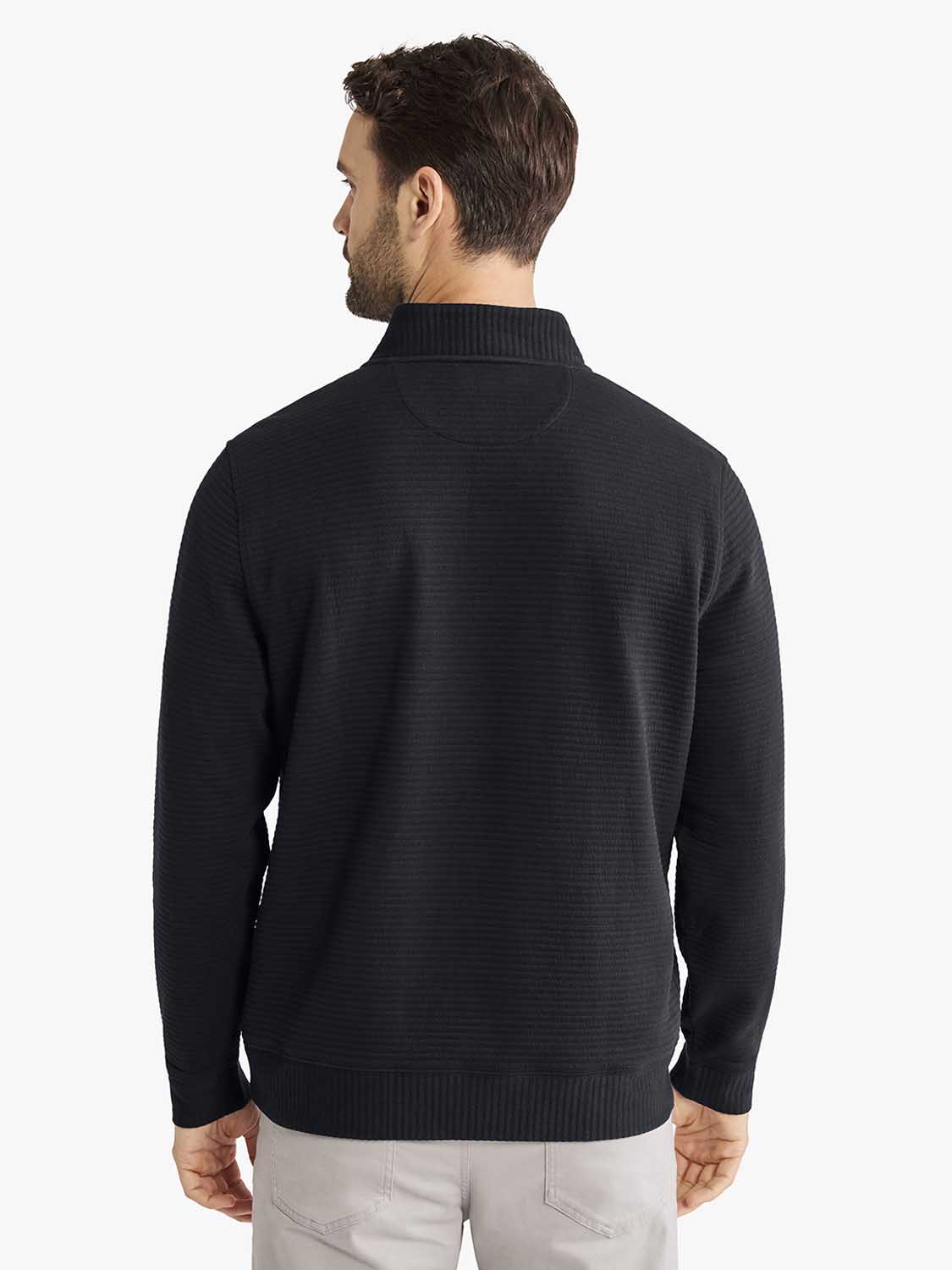 Man wearing black quarter zip pullover with textured knit fabric shown from the back view.