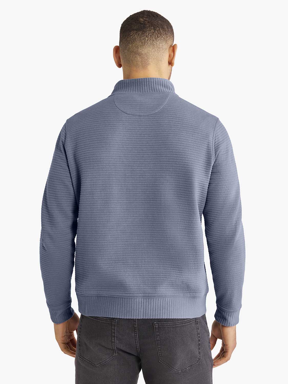 Man wearing a blue quarter zip pullover with textured fabric and ribbed collar, shown from behind.