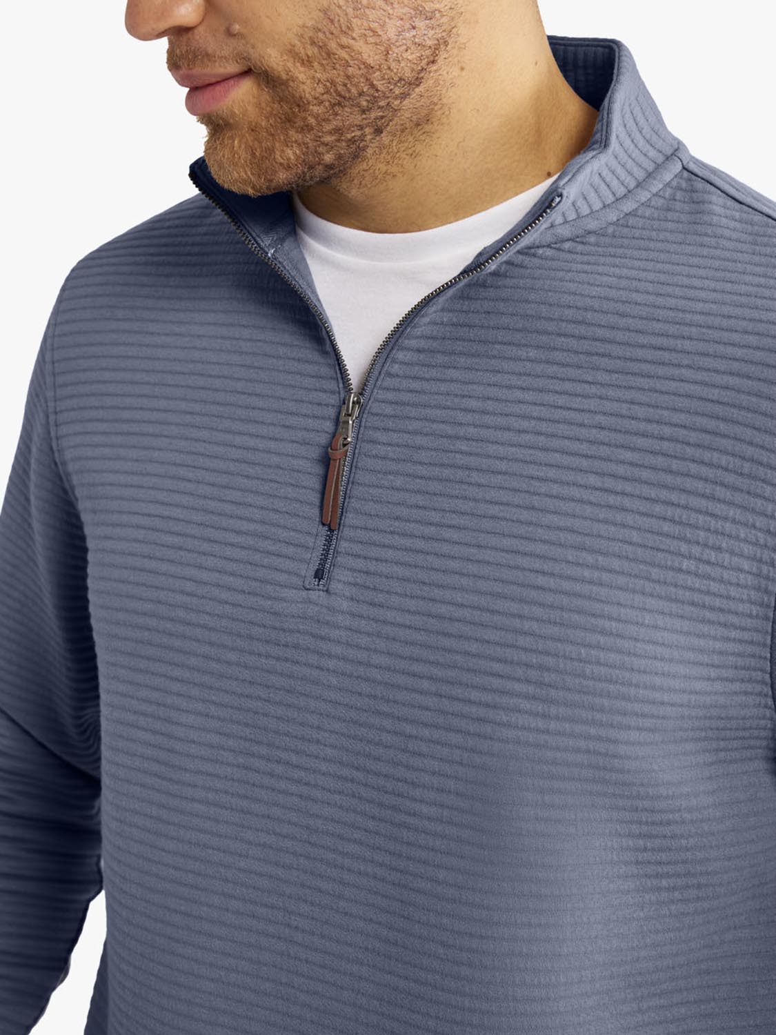 Man wearing a slate blue quarter-zip pullover with ribbed texture and brown zipper pull.