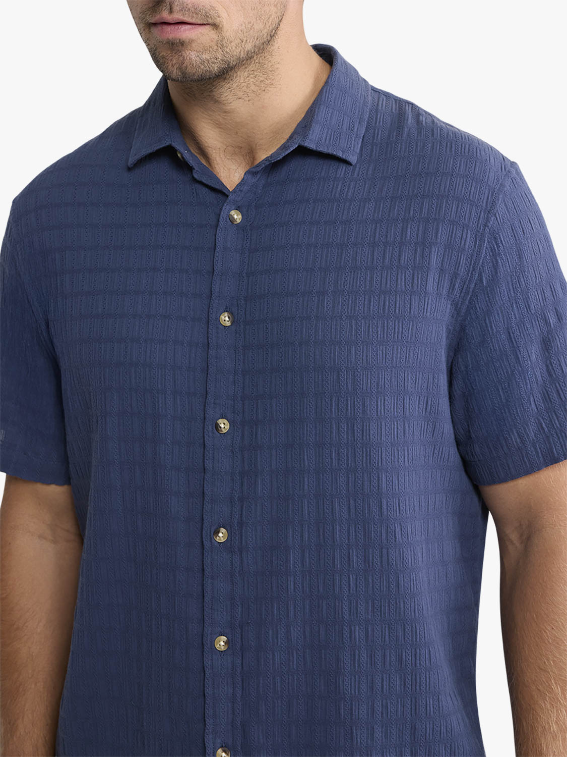 Man wearing a navy basket weave textured short-sleeve button-up shirt with a pointed collar.