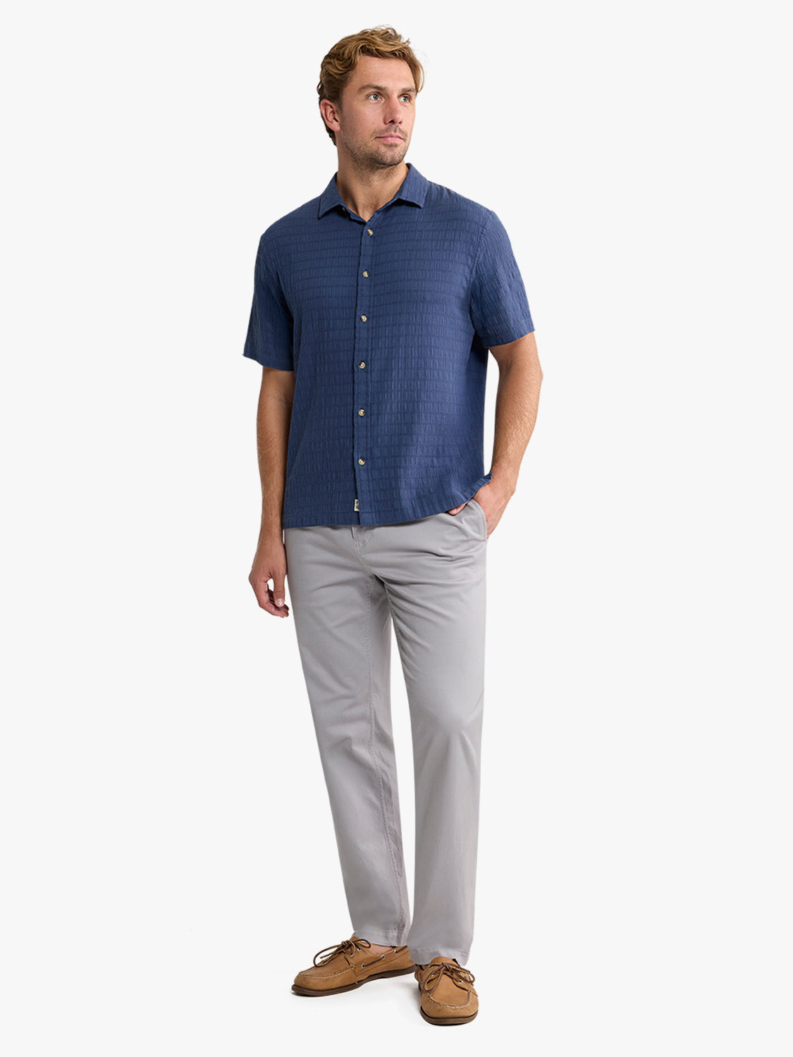 Man wearing navy basket weave short-sleeve shirt with gray pants and brown suede shoes.