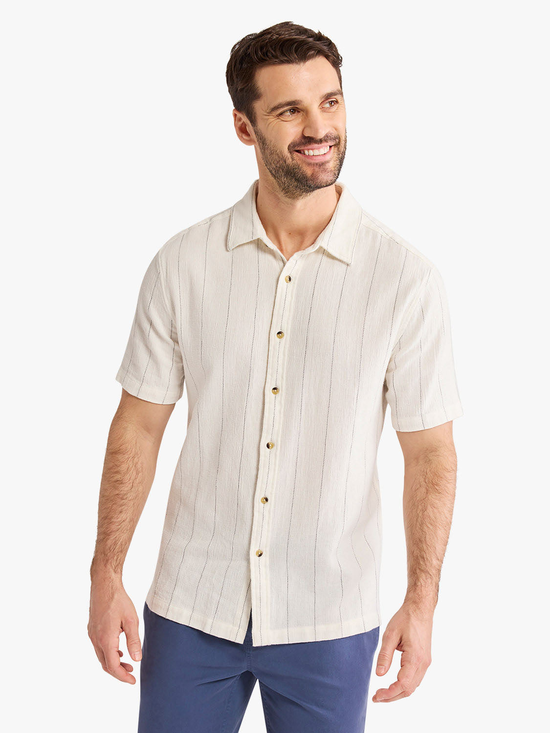 Man wearing a cream short-sleeved textured shirt with vertical stripe pattern and button front.