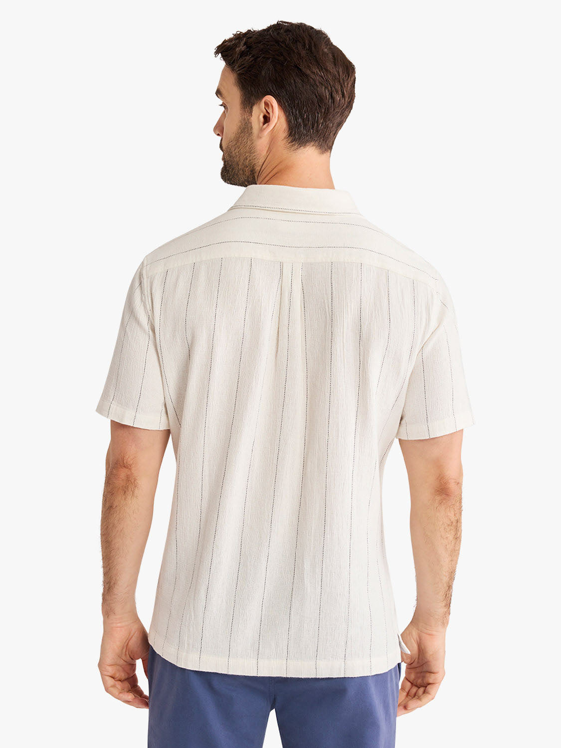 Man wearing a cream-colored short-sleeved shirt with vertical stripe texture pattern.