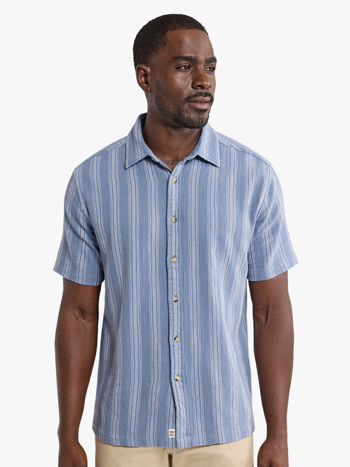 Man wearing a short-sleeved blue and white striped button-up shirt with a textured fabric.