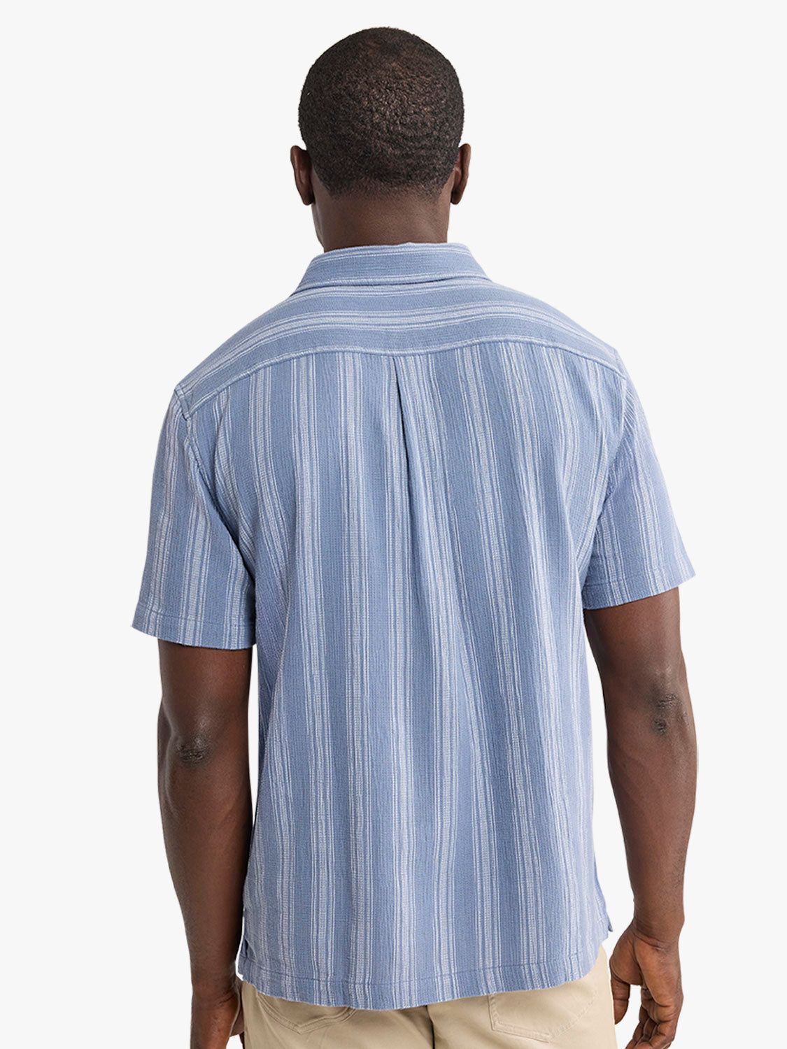 Blue and white striped short-sleeve shirt displayed from the back on a model wearing tan pants.