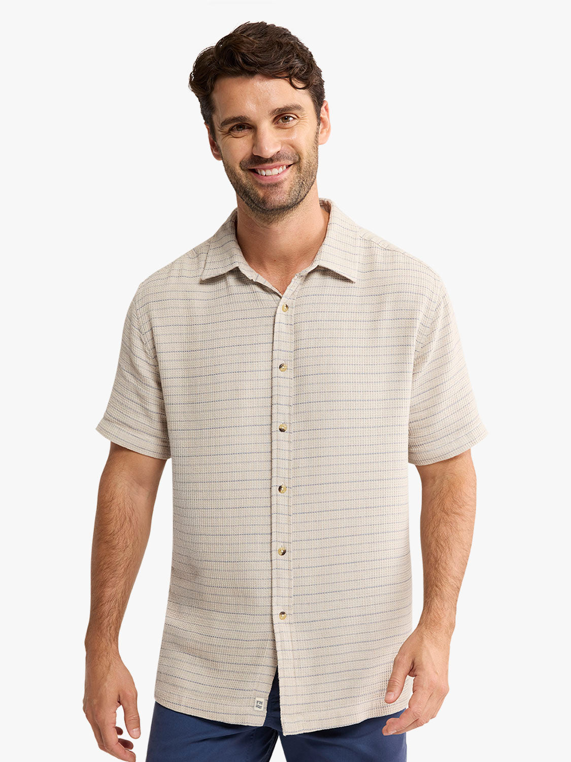 Man wearing a beige striped short-sleeve button-up shirt with a textured weave pattern.