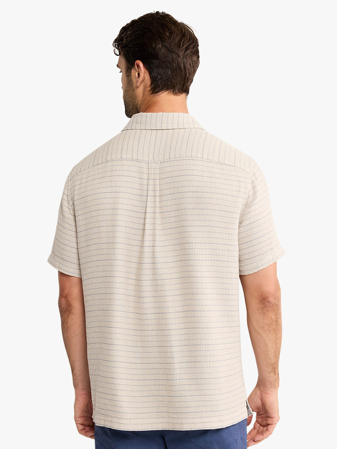 Man wearing a beige short-sleeved button-up shirt with horizontal stripe texture pattern.