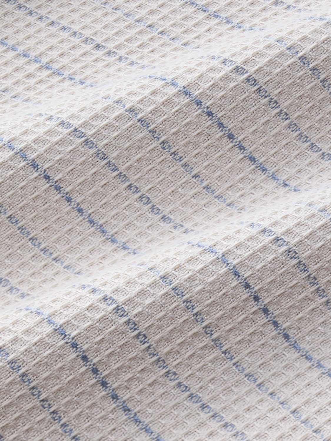 Beige textured fabric with blue vertical stripes woven throughout the material.