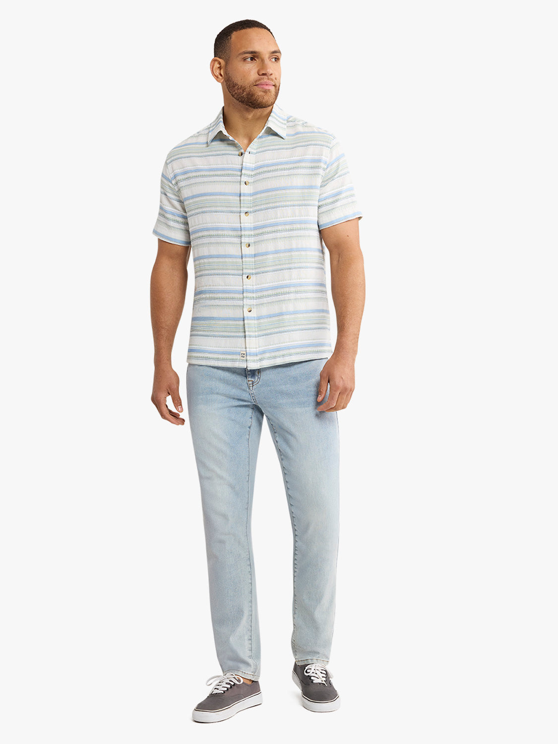 Man wearing a short-sleeved striped shirt in blue and gray tones with light blue jeans.