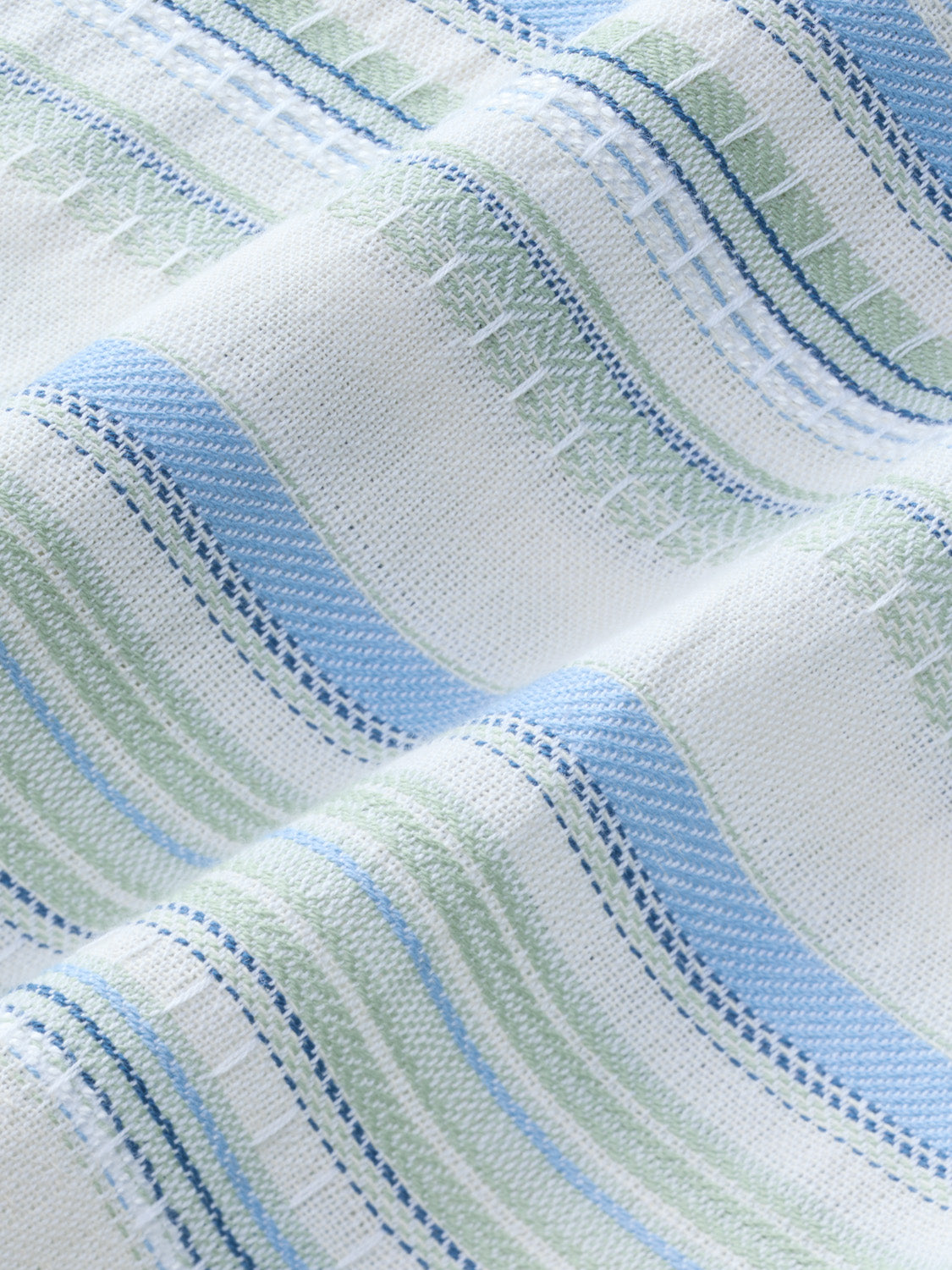 Textured fabric with vertical stripes in blue, green, and white colors showing woven detail.