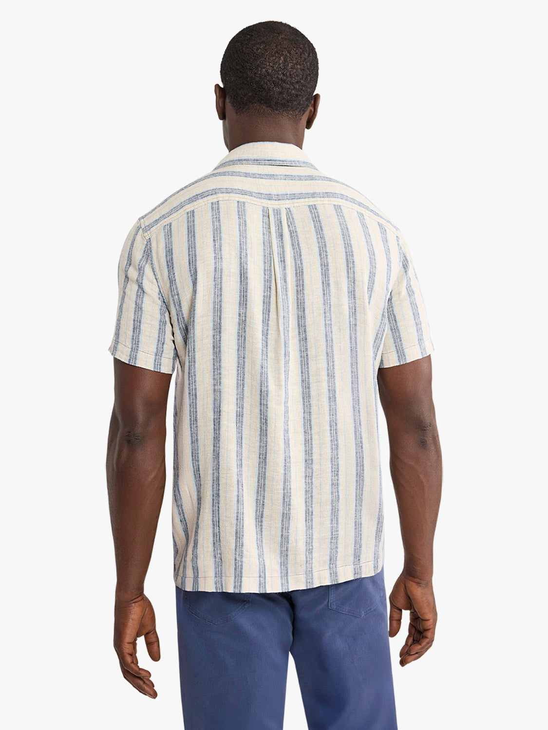 Man wearing a cream and blue striped short-sleeved shirt with textured fabric, shown from behind.
