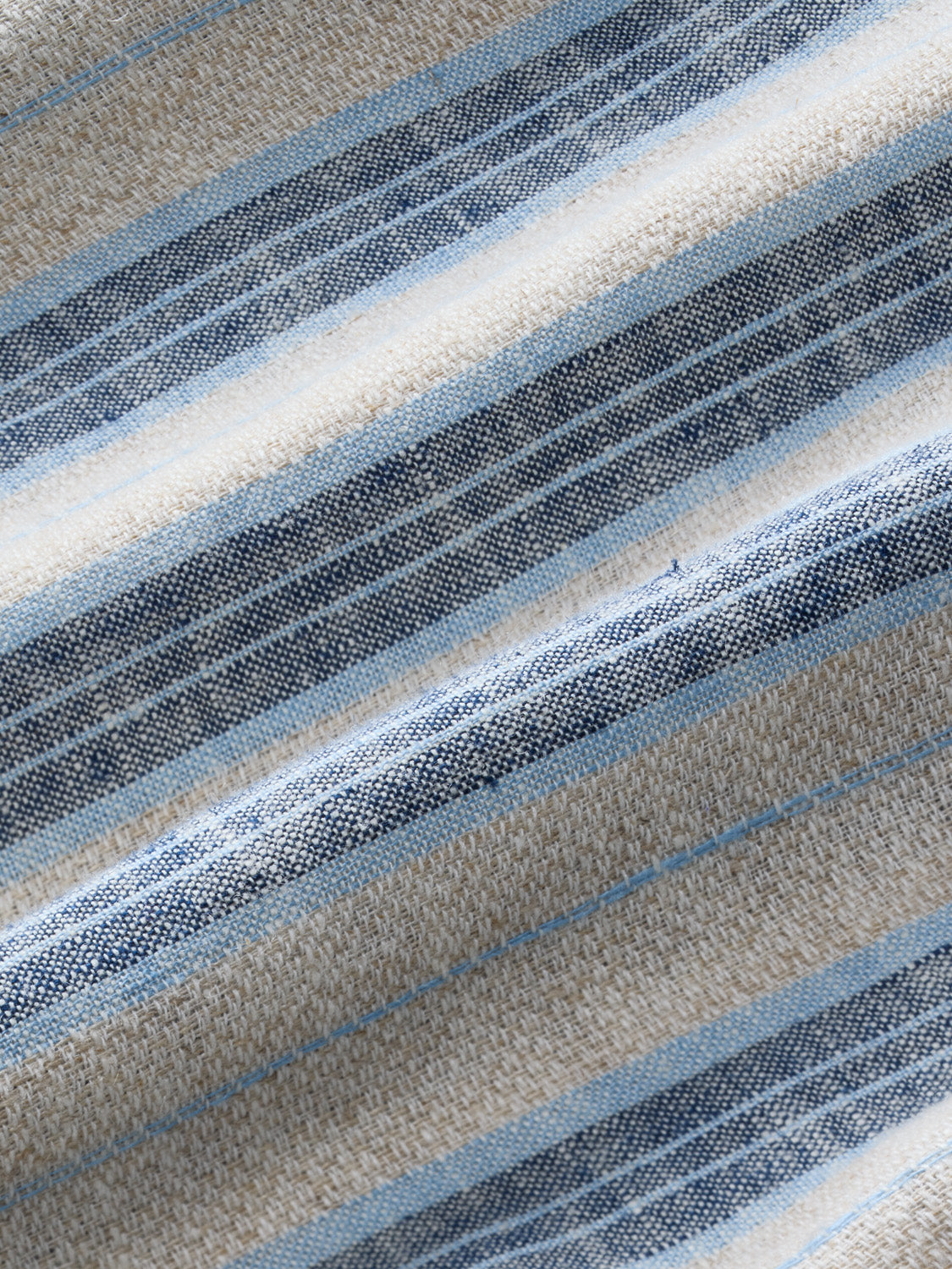 Close-up detail of textured fabric showing horizontal stripes in sea blue, navy, cream, and beige tones.