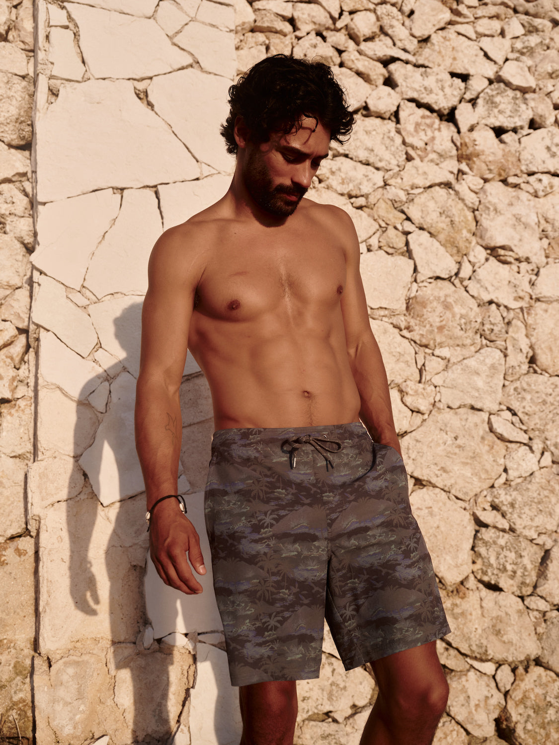 Man wearing pair of ozone shorts against a stone wall.  