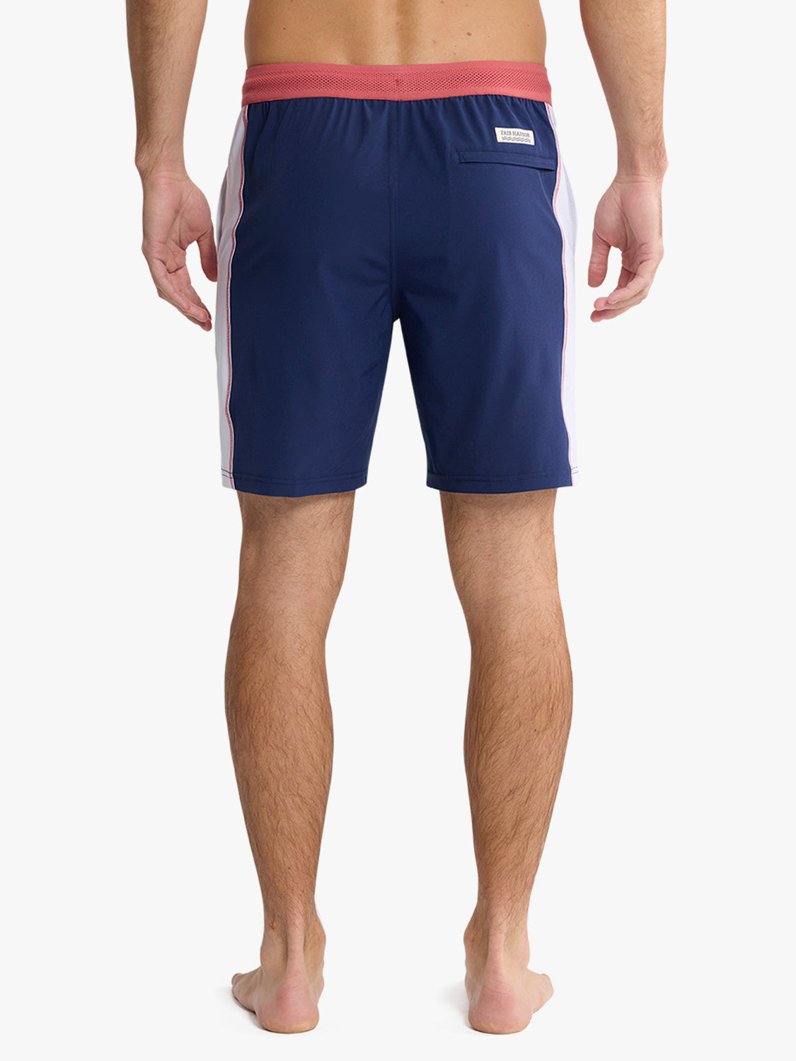 Navy board shorts with red waistband and light pink side stripes shown from behind.