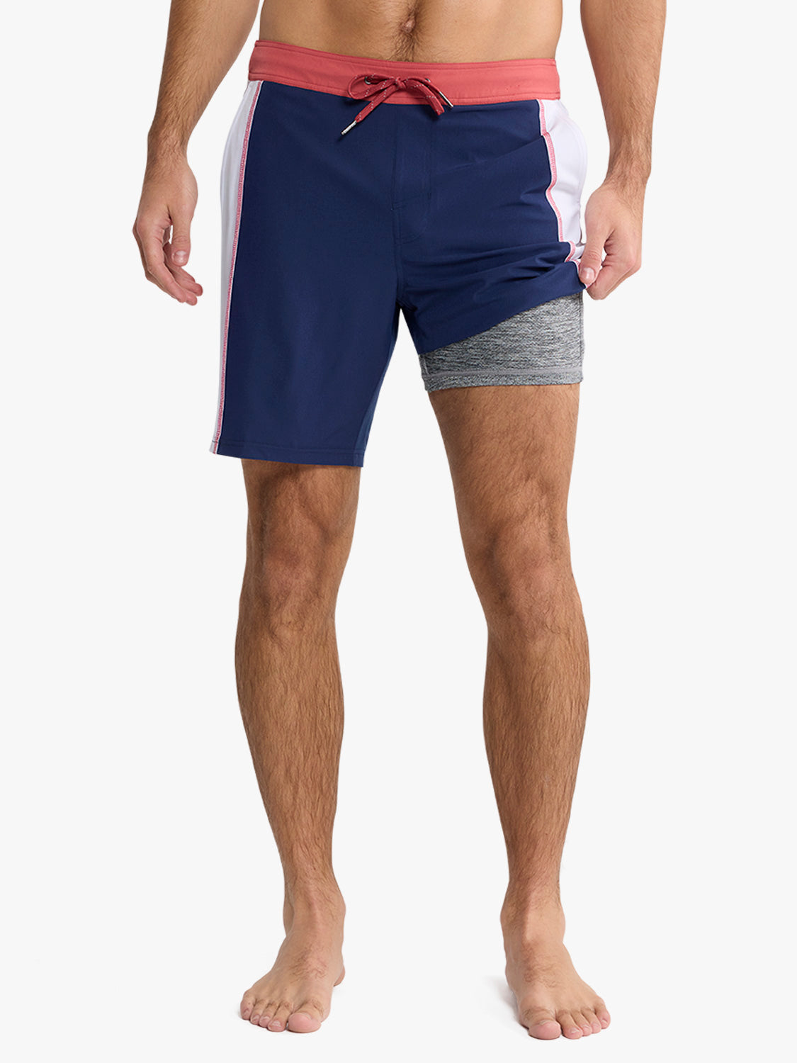 Navy, red, and white colorblock board shorts with a red drawstring waistband on a man.