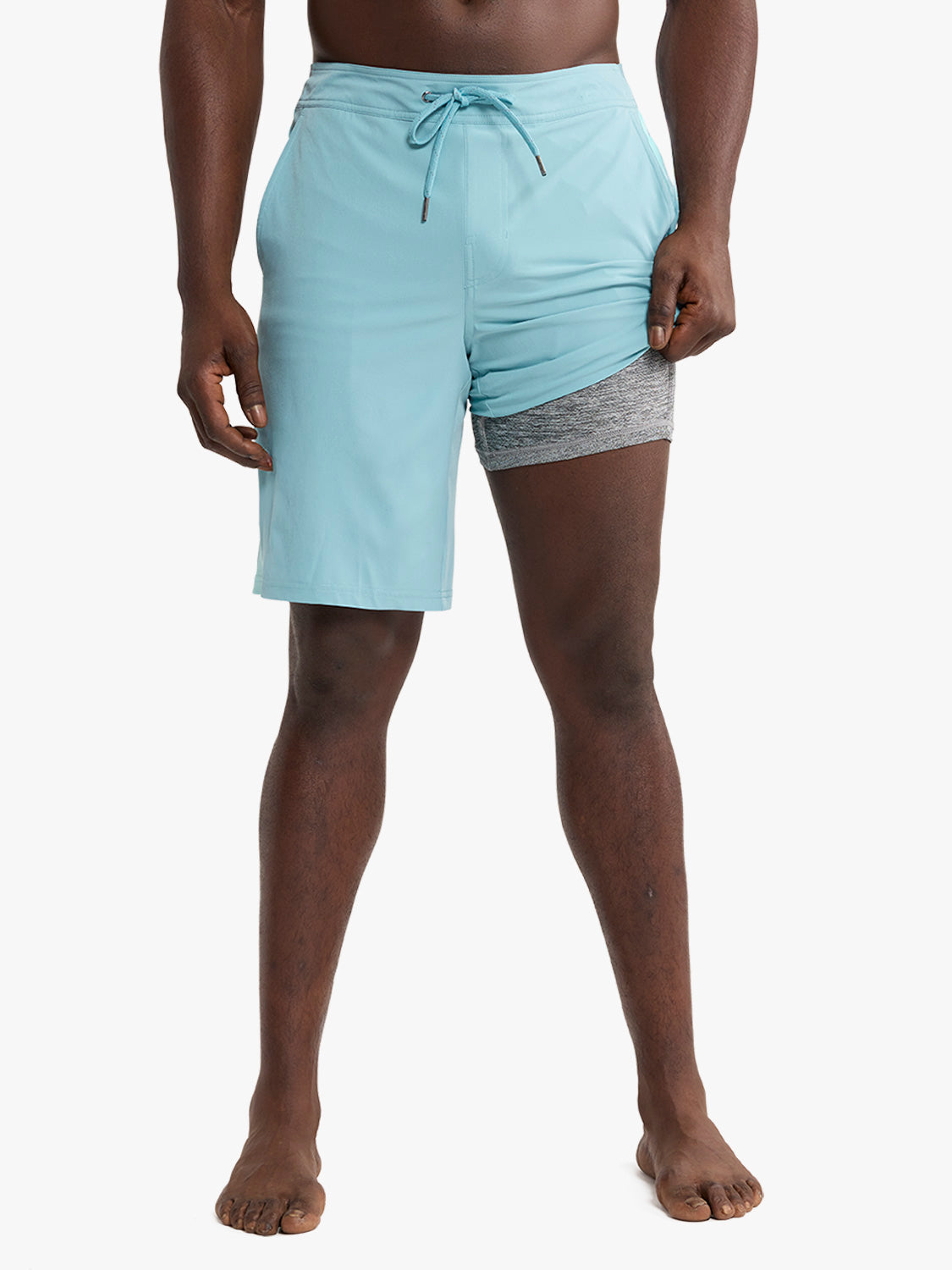 Man wearing light blue swim shorts with gray striped inner lining and drawstring waistband.