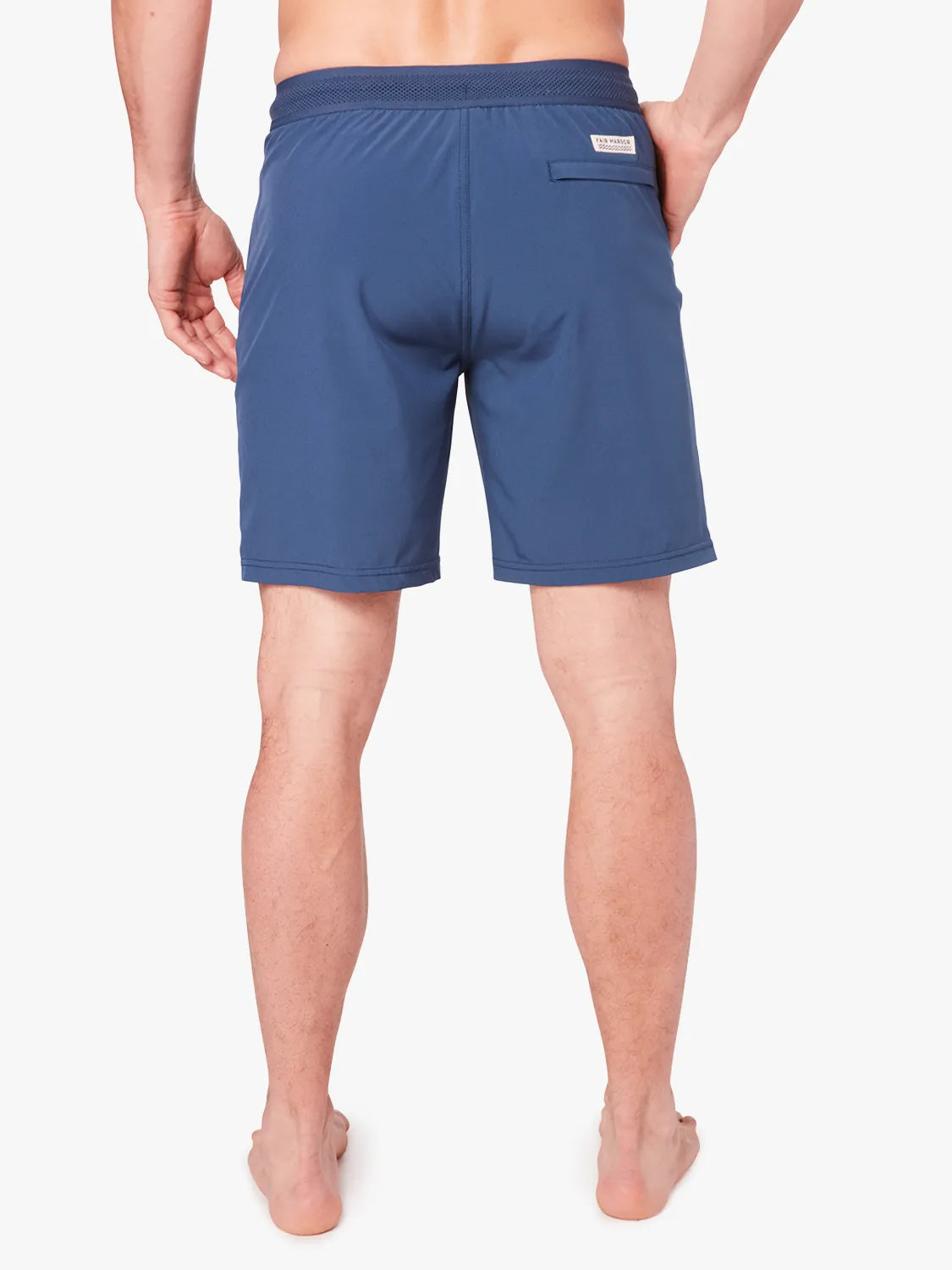 Person wearing a pair navy blue ozone trunks with a drawstring on a white background, showing back view.