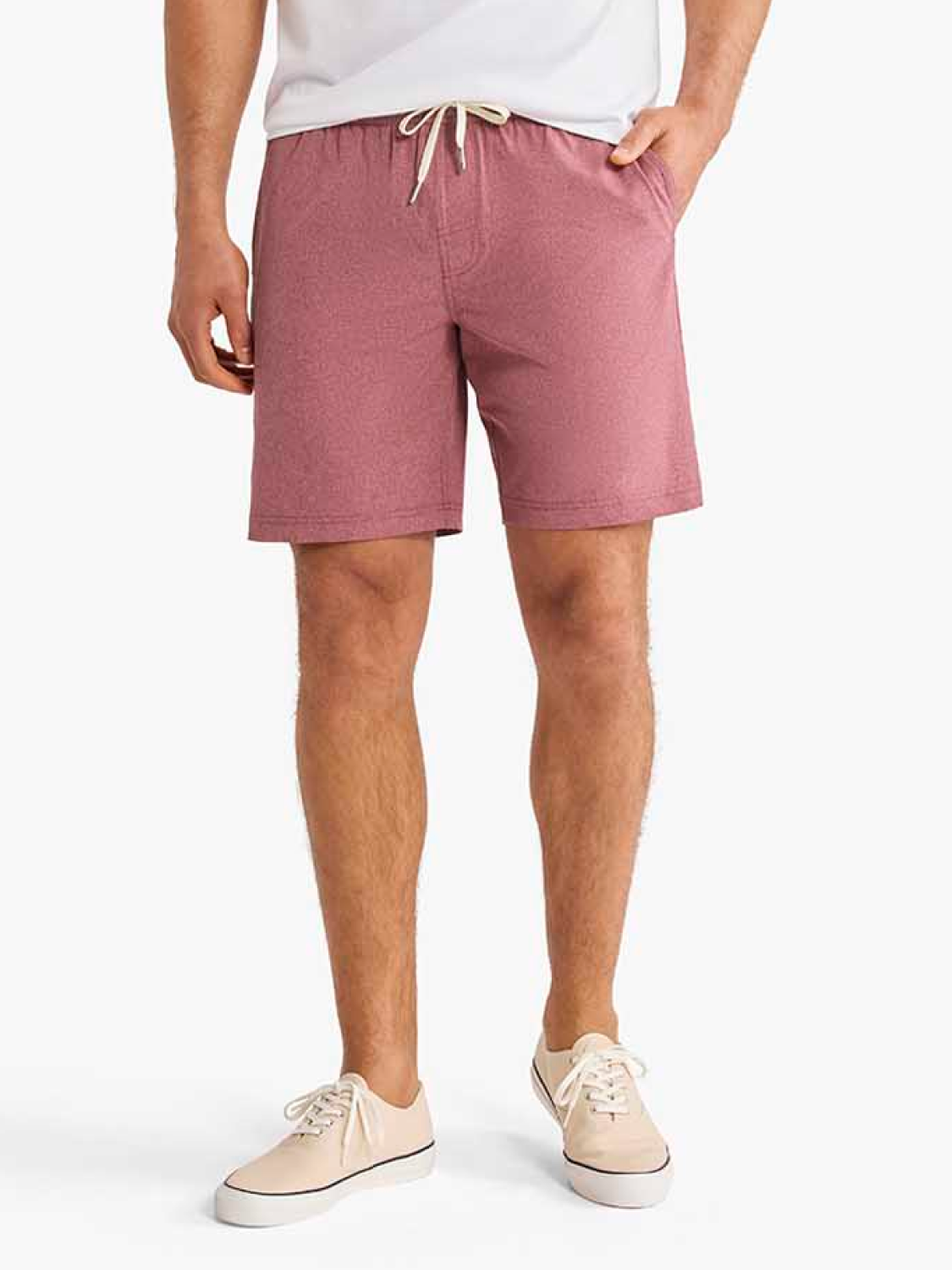 Man wearing white t-shirt and burgundy shorts with drawstring waist and cream sneakers.