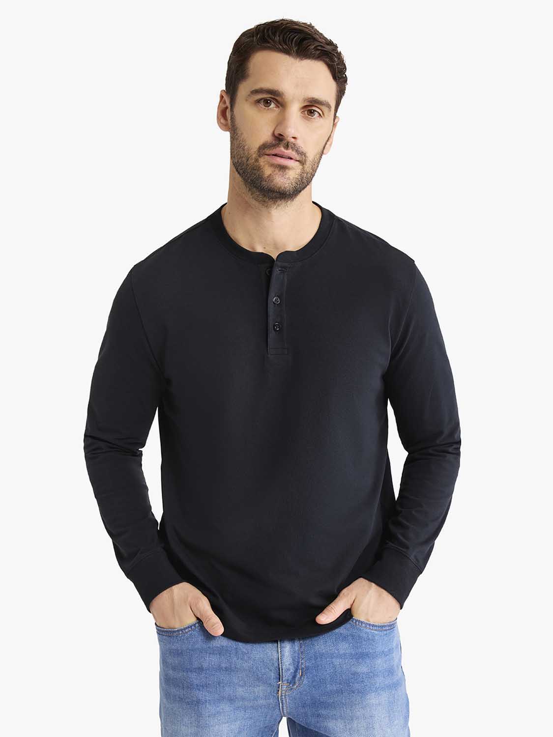 Man wearing black long-sleeve Henley shirt with button placket and blue jeans.