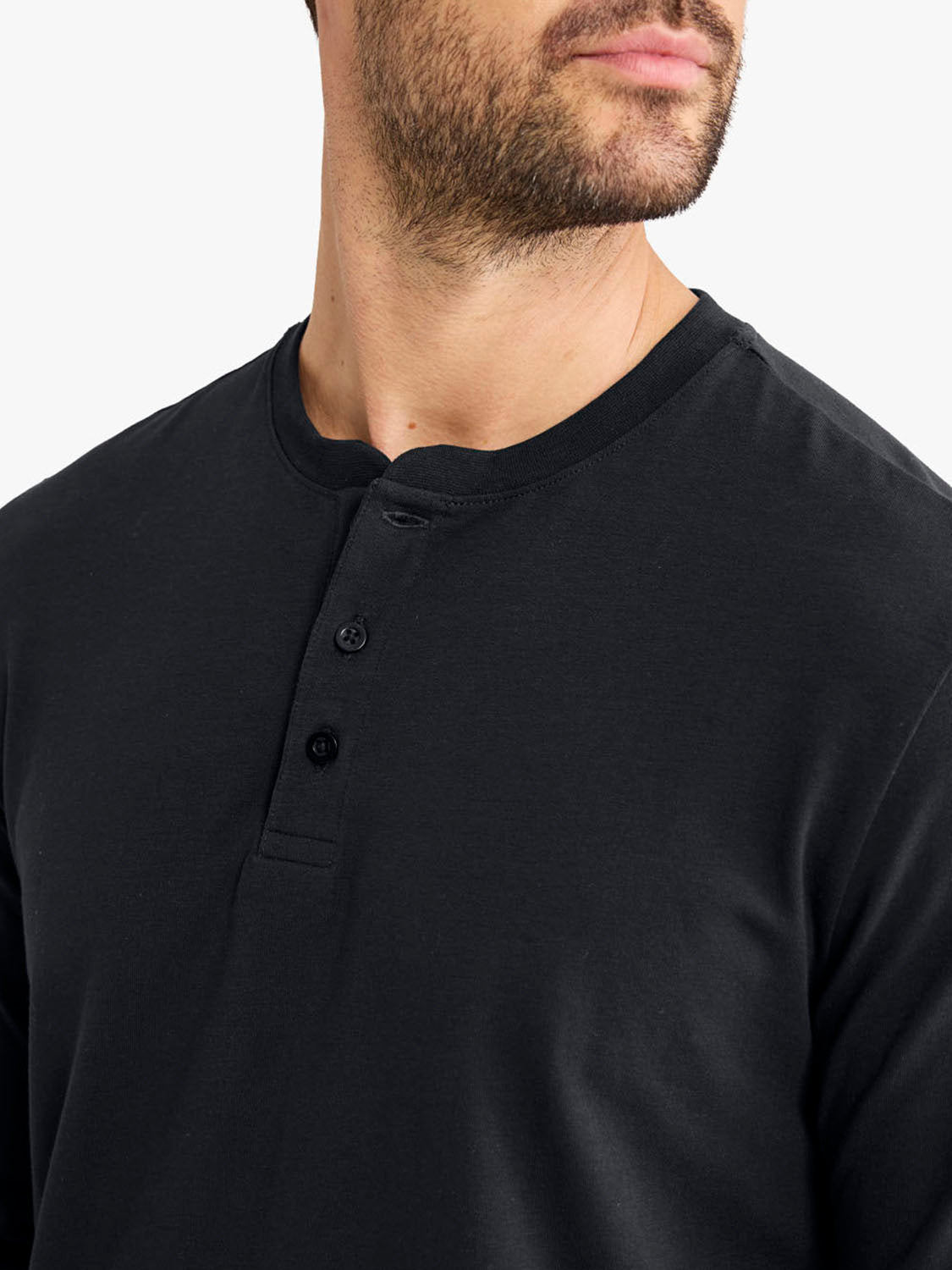 Man wearing a black Henley shirt with button placket detail at the neckline.