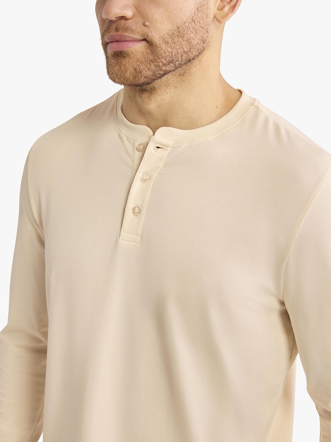 Man wearing a cream-colored long-sleeve Henley shirt with button placket detail.