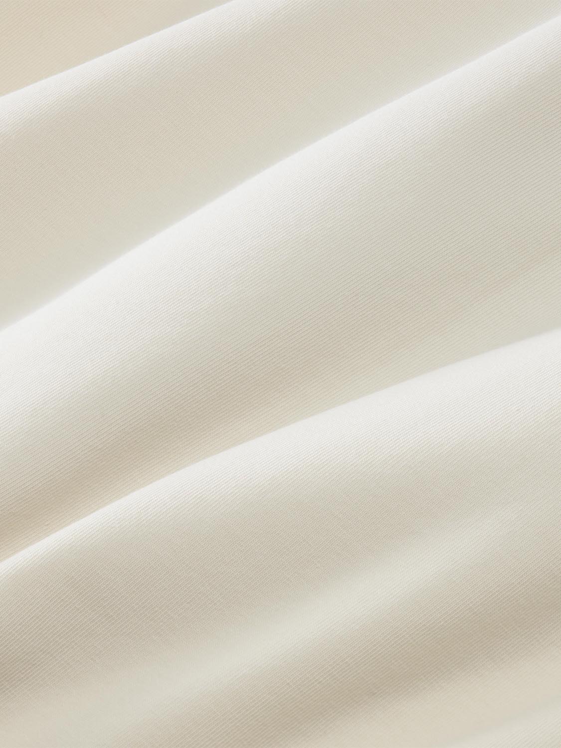 Cream-colored ribbed fabric with subtle texture and soft folds displayed against a neutral background.