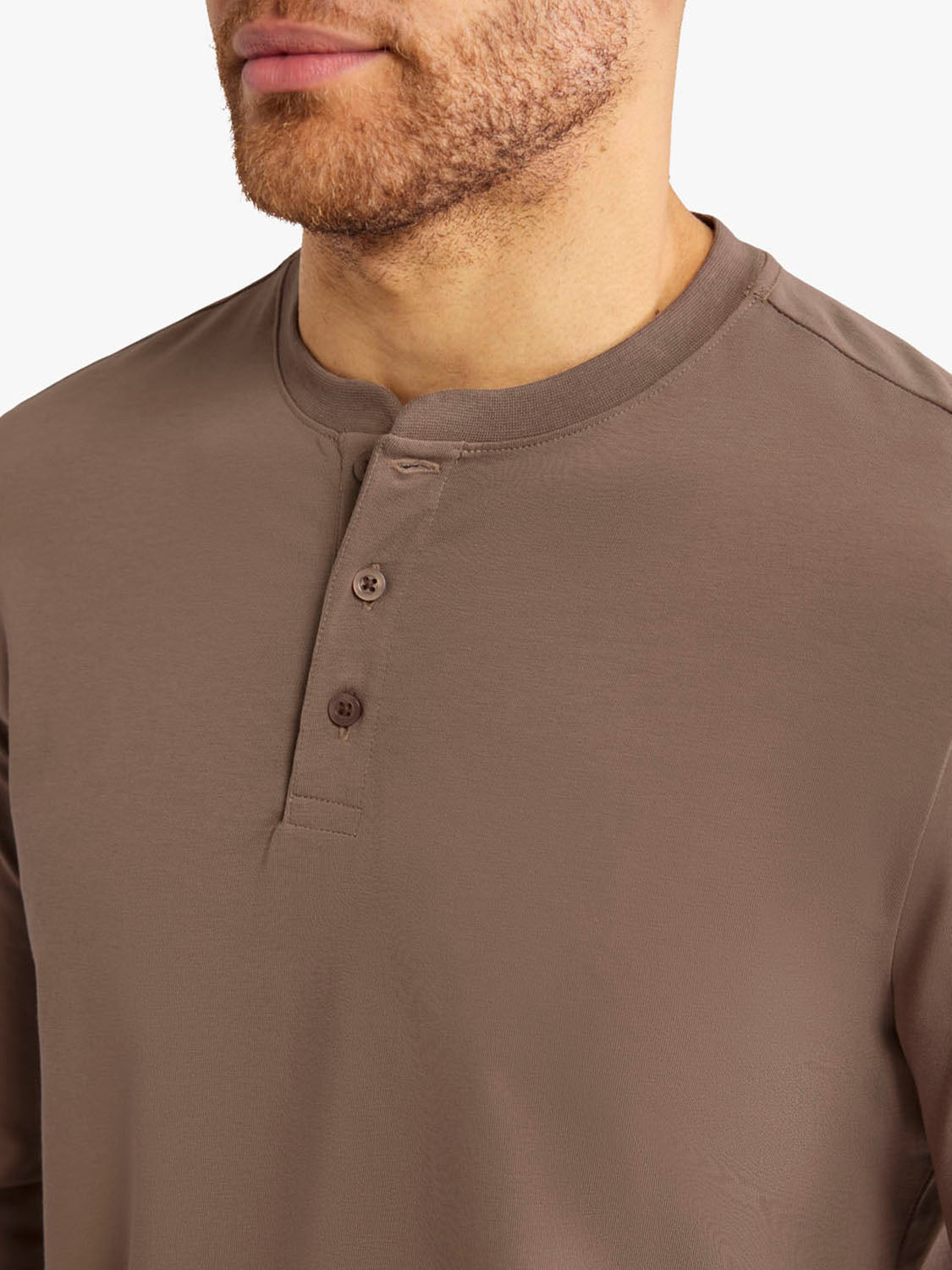 Man wearing a sandbar-colored long-sleeve henley shirt with button front placket.