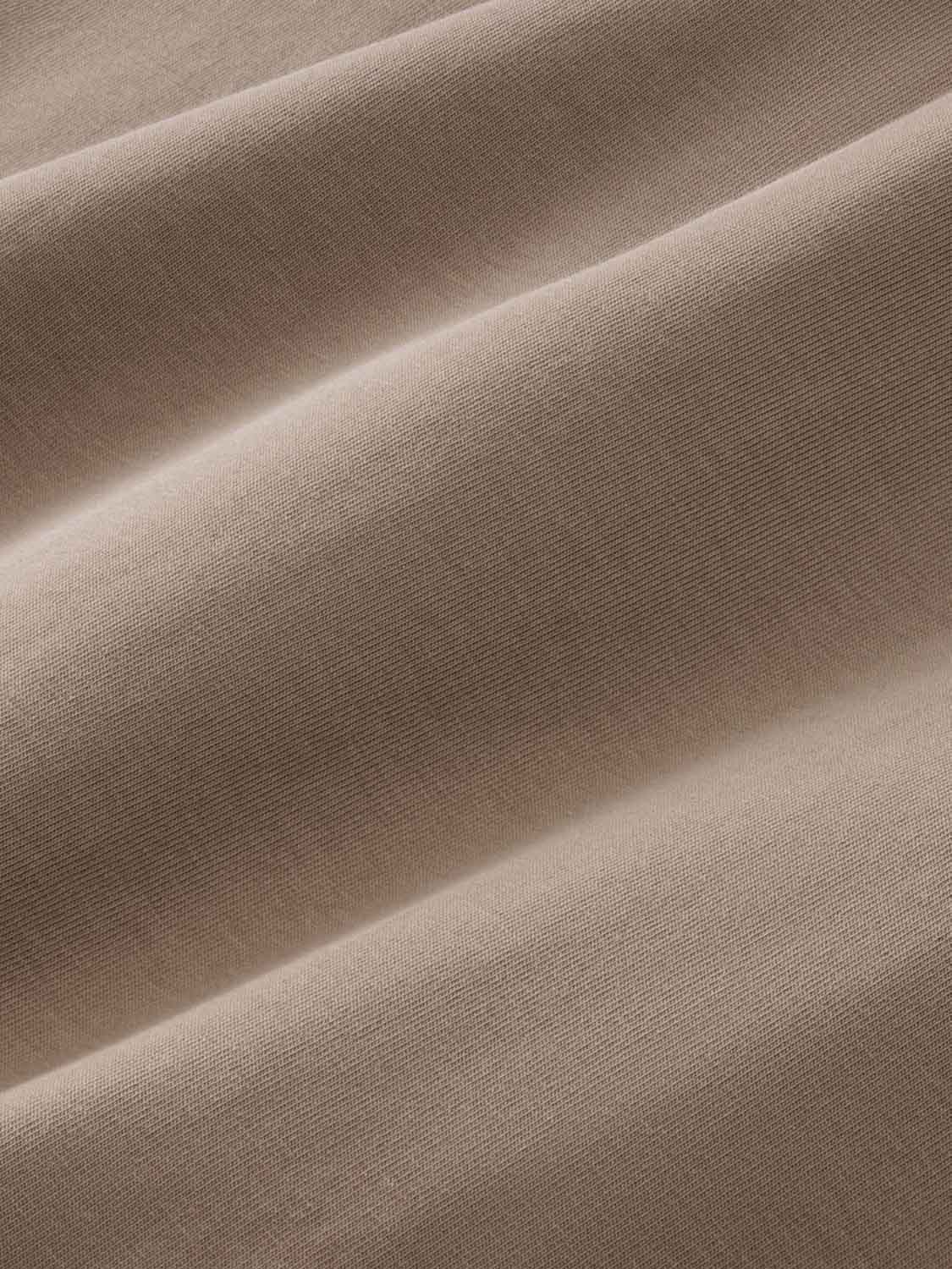 Close-up of beige ribbed fabric with soft folds and draped texture throughout.