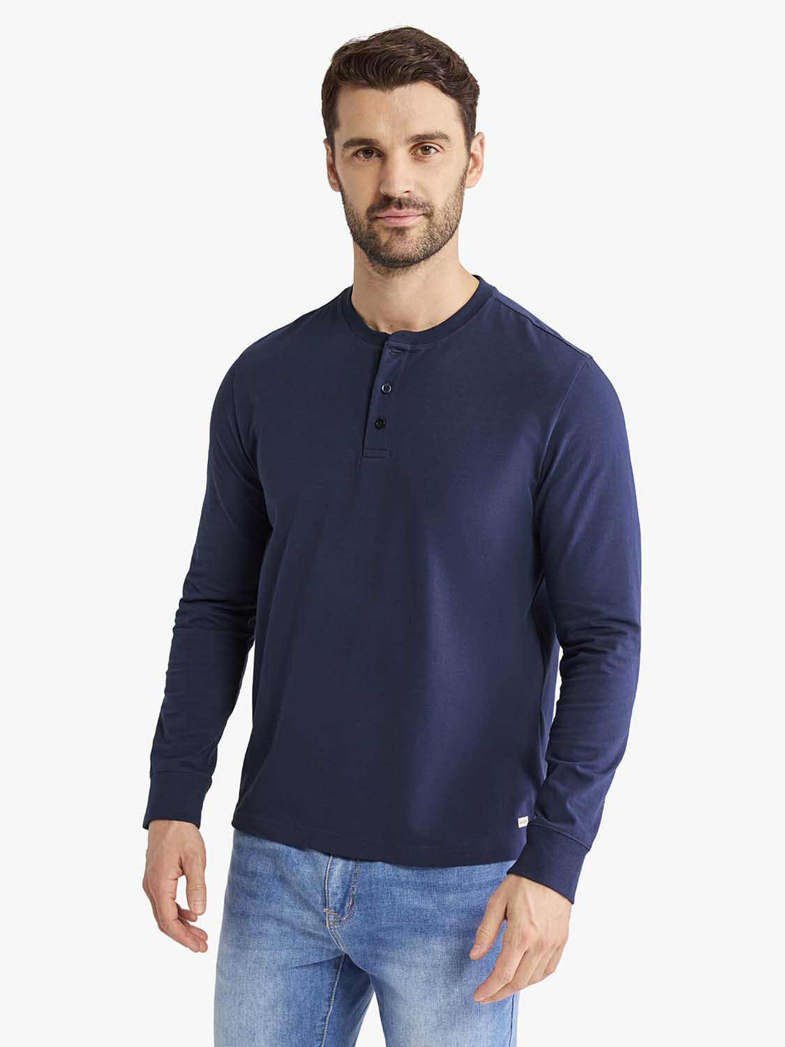 Man wearing a navy blue long-sleeve henley shirt with button placket and blue jeans.