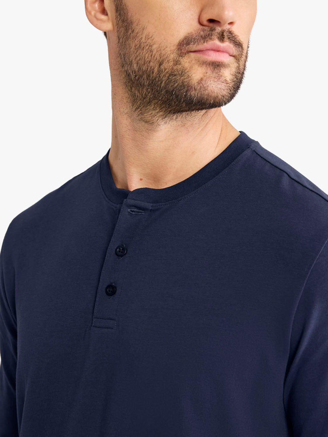 Man wearing a navy blue long-sleeve henley shirt with button placket detail.