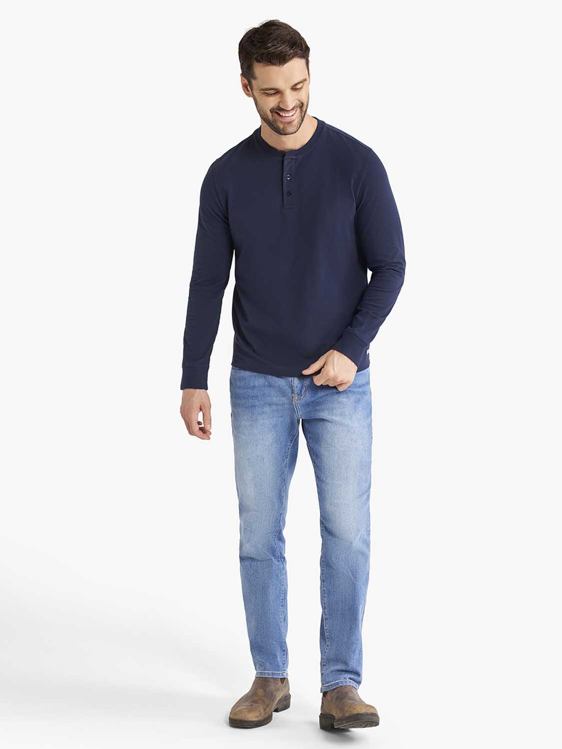 Man wearing a navy long-sleeve henley shirt with button placket and light blue jeans.