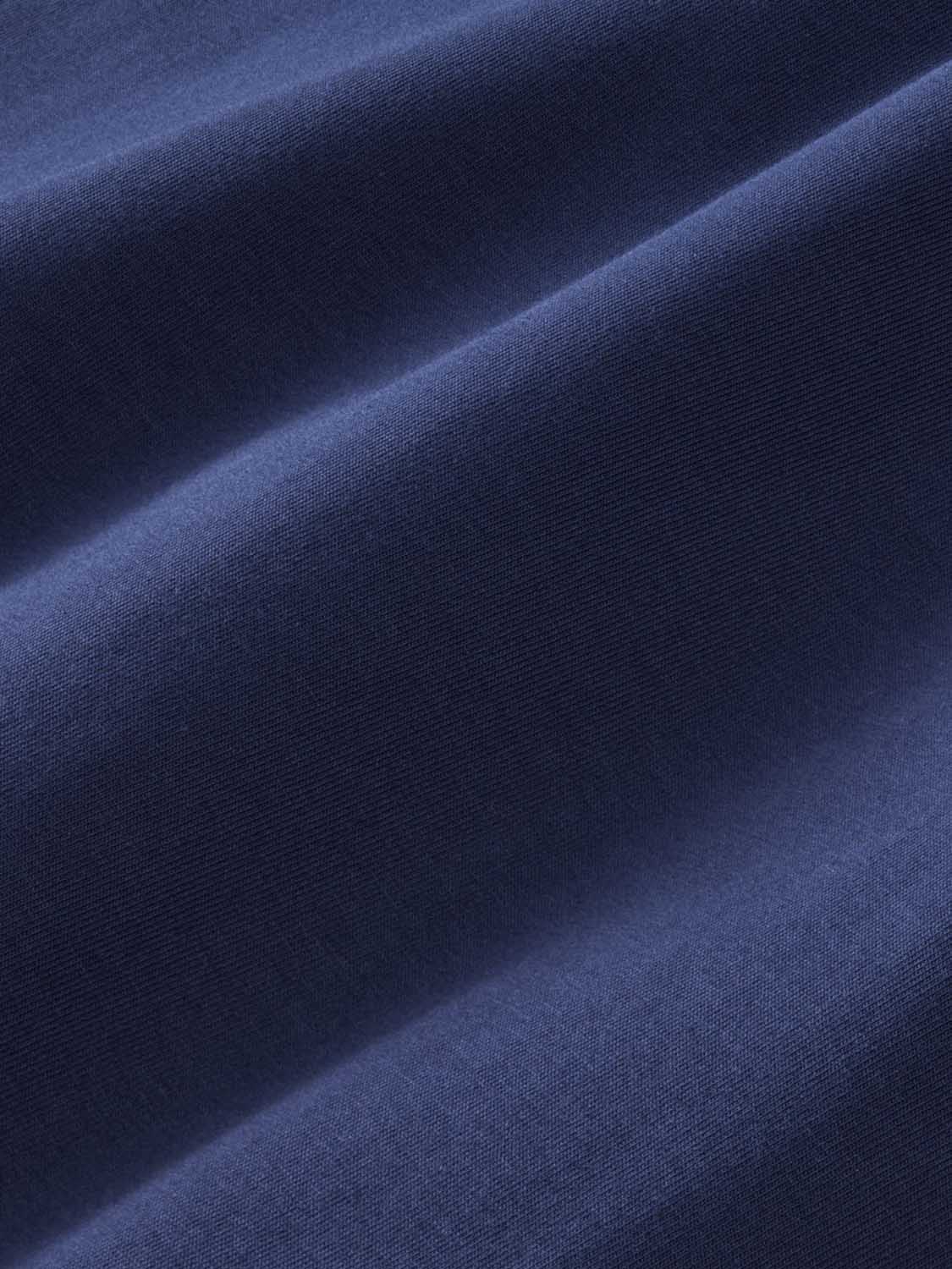 Close-up of navy ribbed fabric with diagonal fold and textured surface detail.