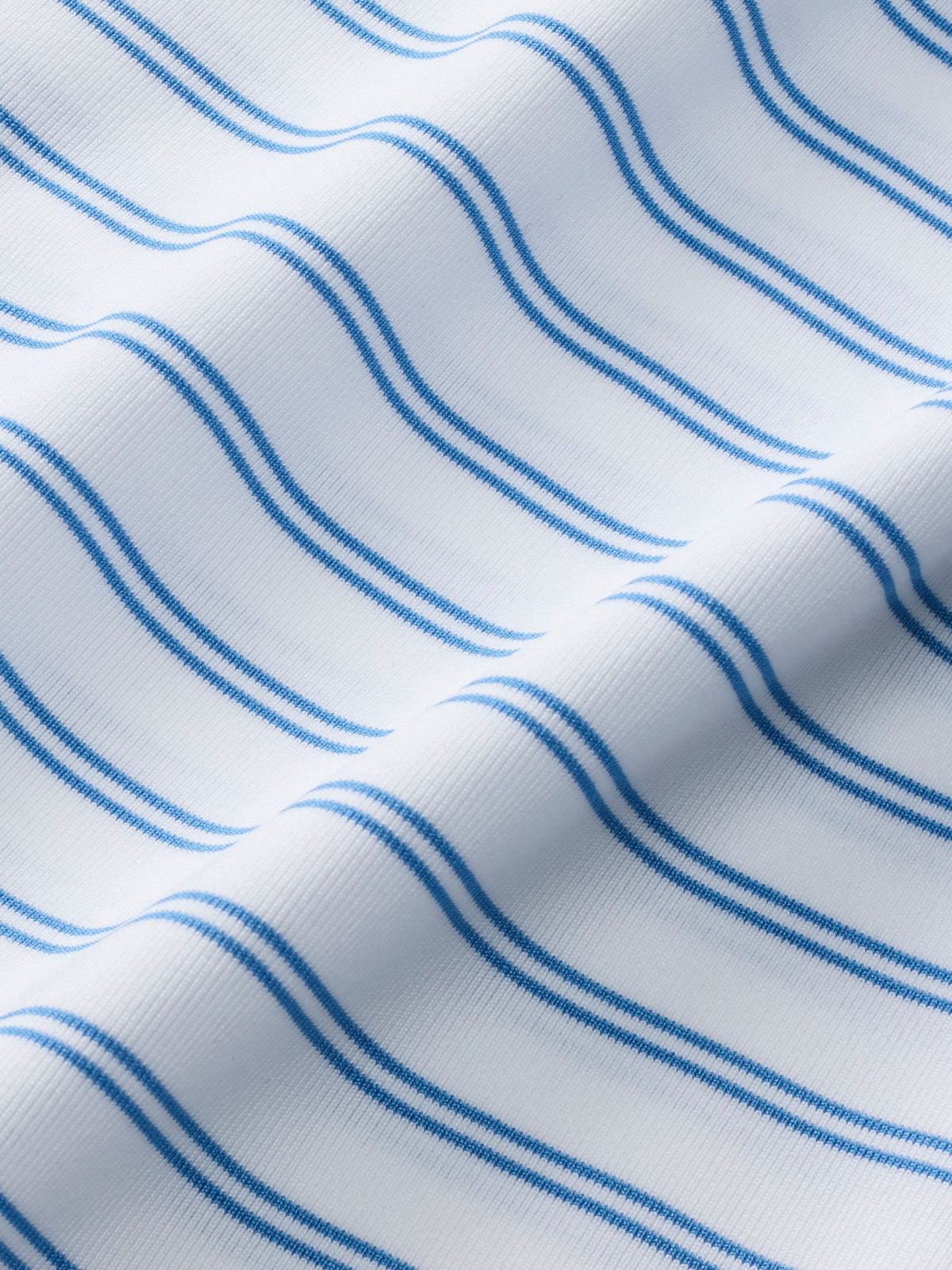 White polo fabric with diagonal blue stripes in varying widths and shades.