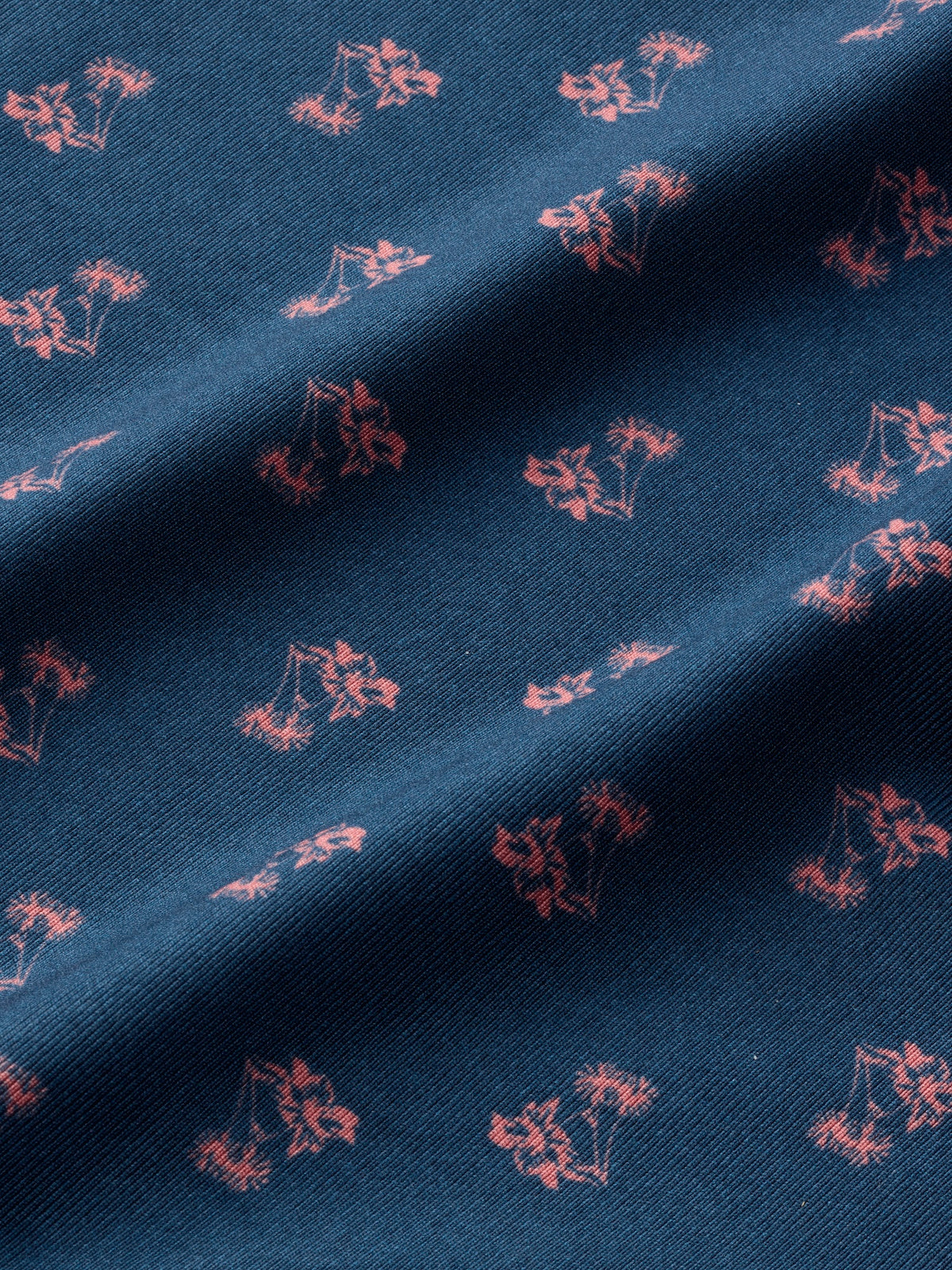 Blue polo fabric with a repeating coral floral print pattern throughout.