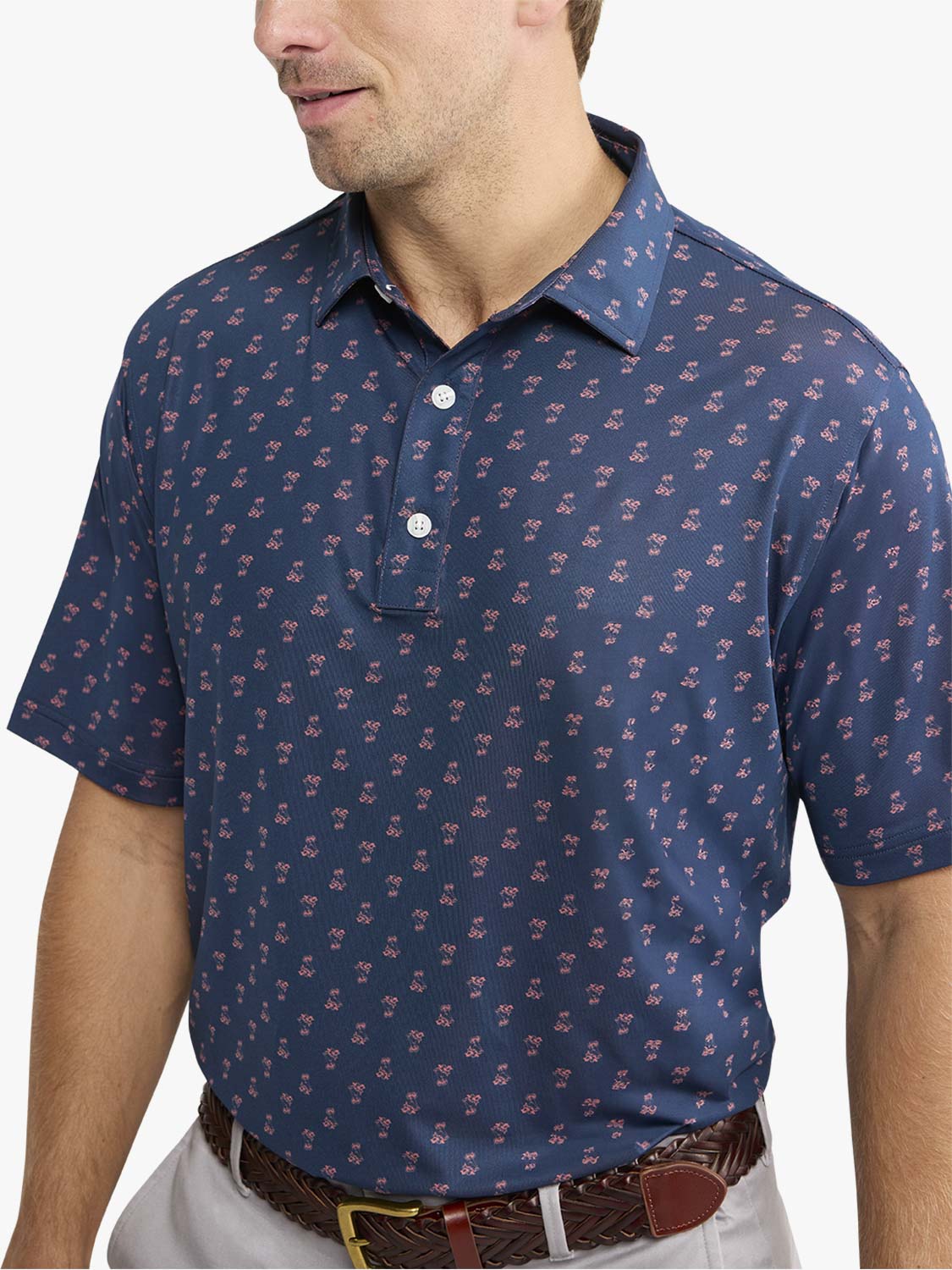Man wearing a navy short-sleeve polo shirt with a small red floral pattern throughout the fabric.