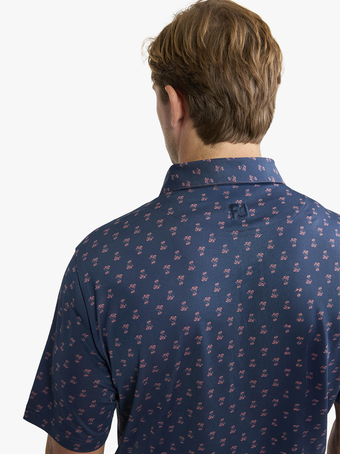 Man wearing a navy blue polo shirt with a small red floral print pattern throughout the fabric.