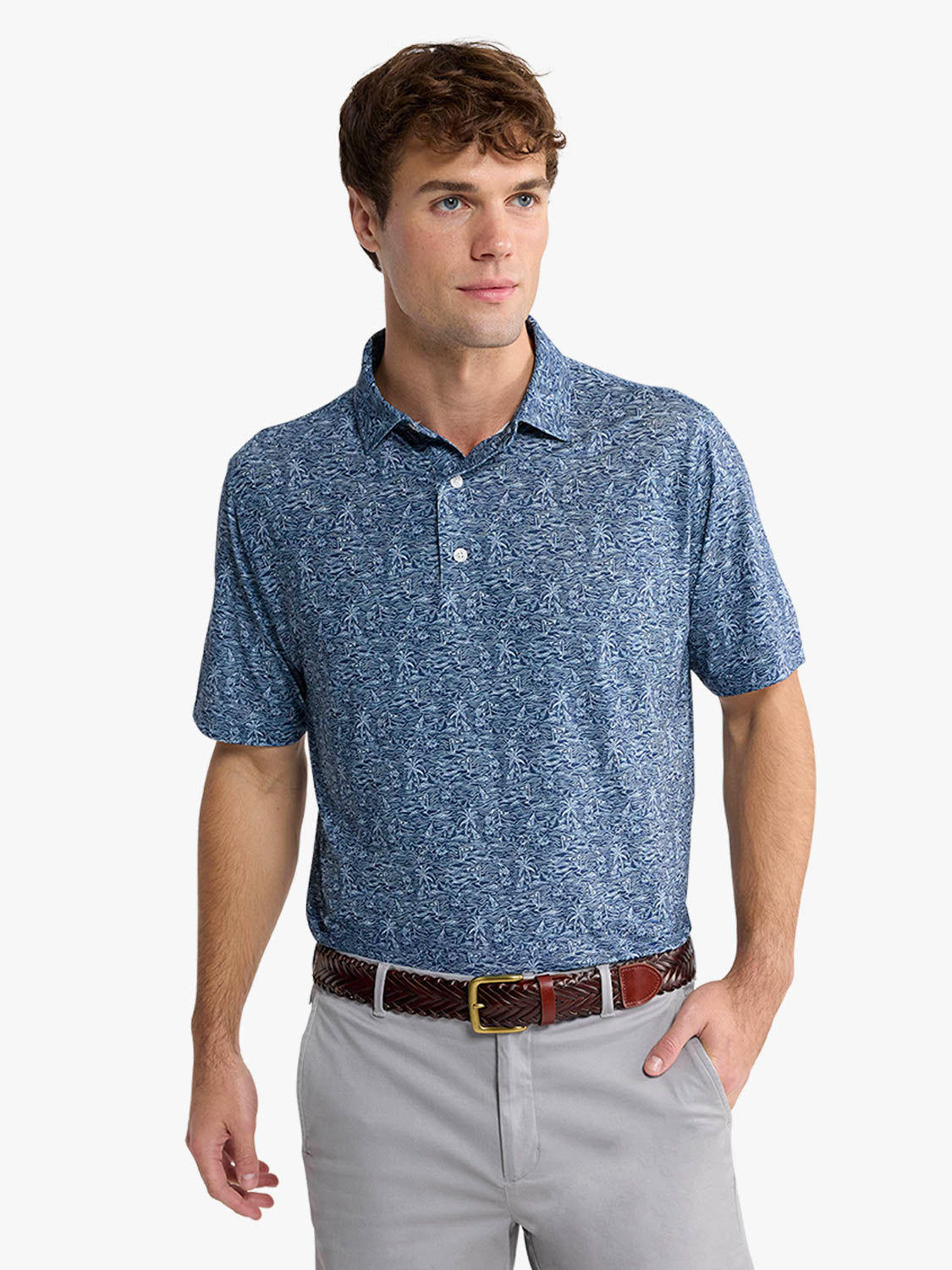 Man wearing a blue tropical print polo shirt with white buttons and light gray pants.
