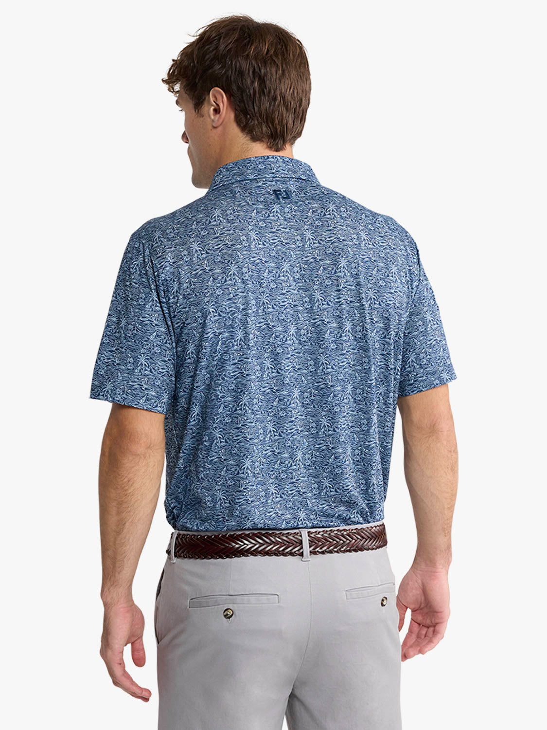 Man wearing a blue patterned polo shirt with gray pants and brown woven belt.