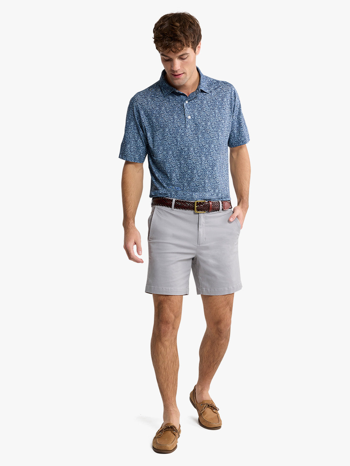 Man wearing a blue heathered polo shirt with gray shorts and brown boat shoes.