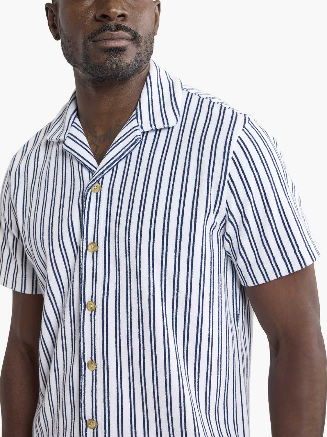 Man wearing a white short-sleeve button-up shirt with blue vertical stripes and gold buttons.