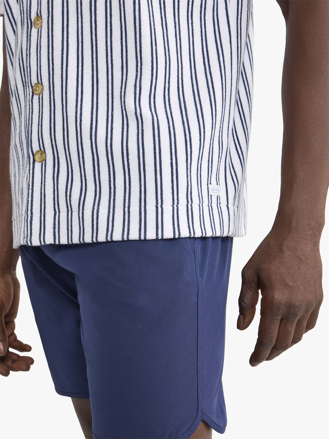 White short sleeve button-up shirt with navy vertical stripes and gold buttons displayed on model.