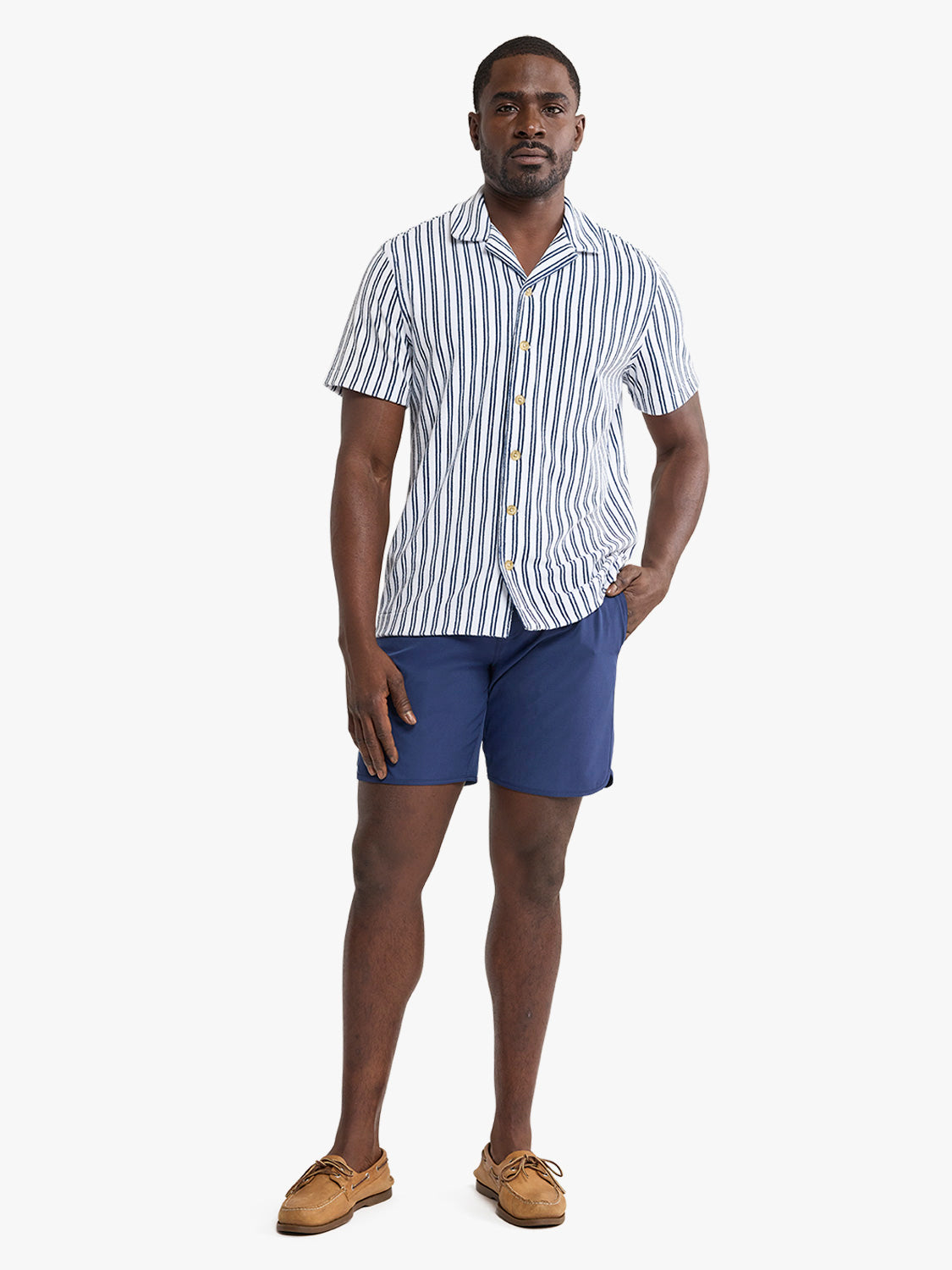 Man wearing white short sleeve button-up shirt with vertical navy stripes and navy shorts.