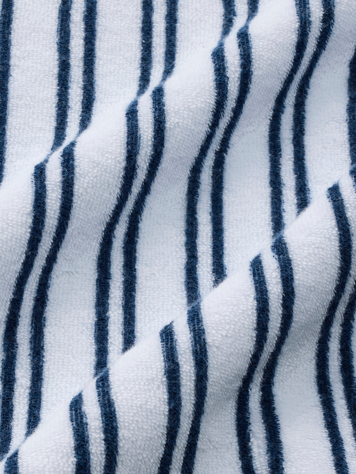 Close-up of white terry fabric with navy vertical striped pattern showing textured surface detail.
