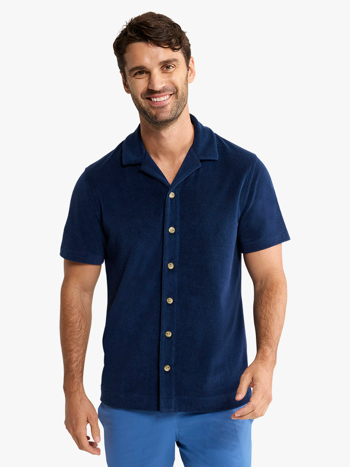 Man wearing a navy terry short sleeve button-up shirt with a spread collar and gold buttons.