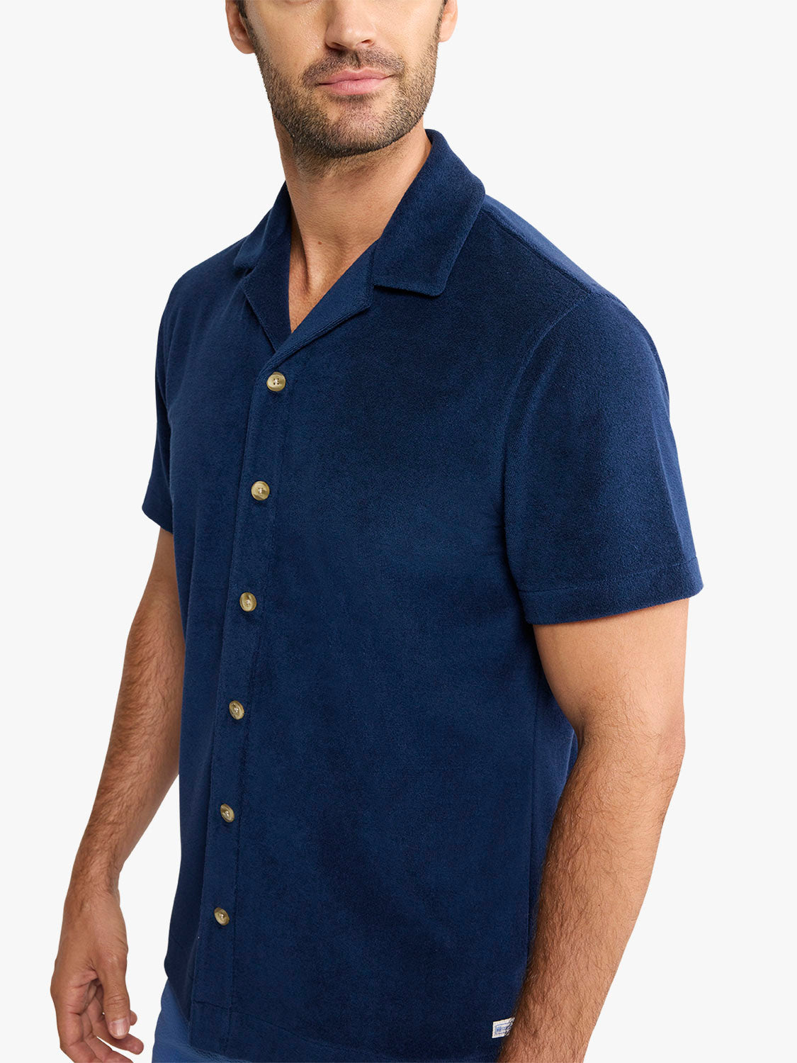 Man wearing a navy terry short sleeve button-up shirt with a relaxed collar and gold buttons.