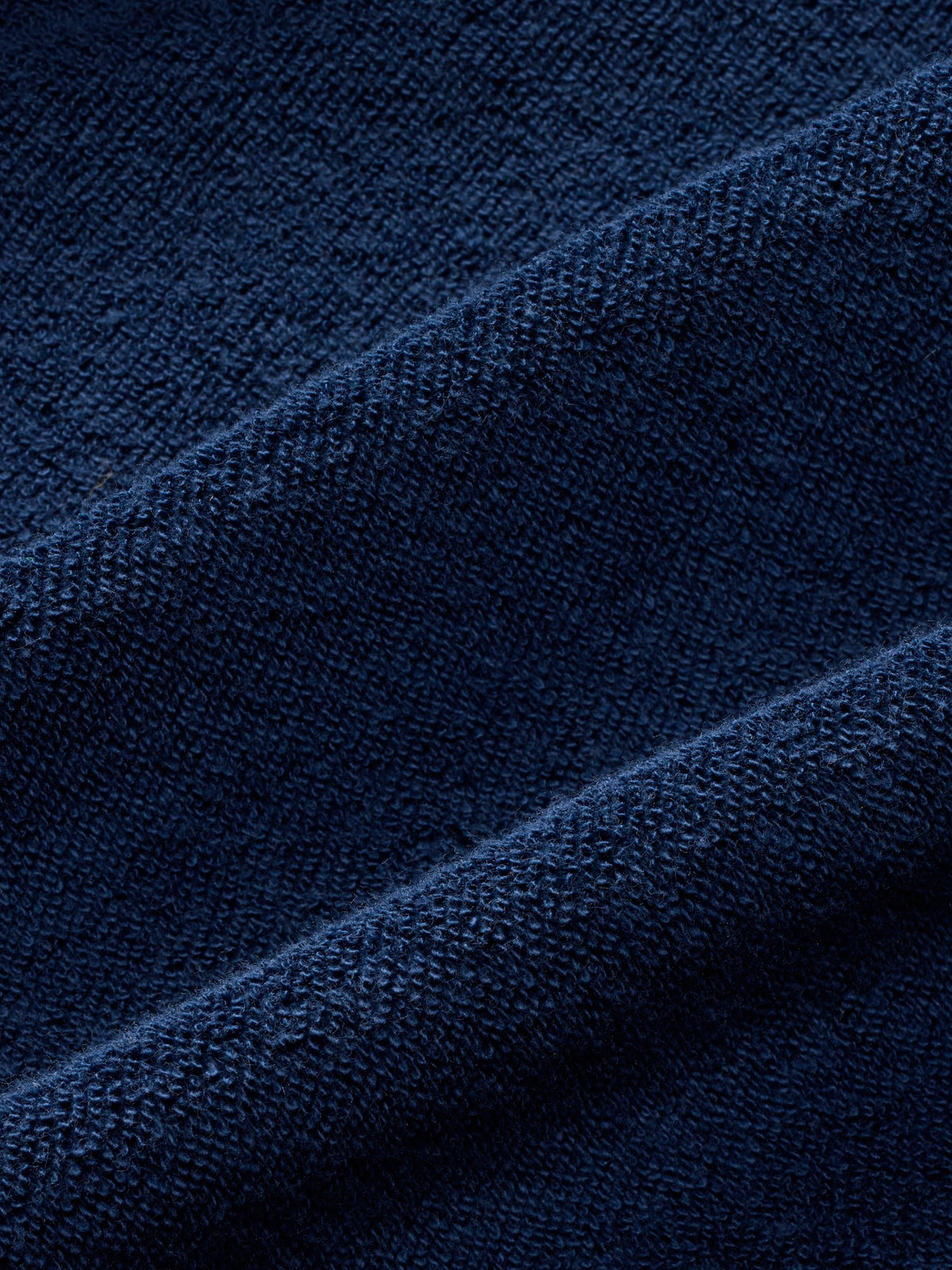 Close-up of navy terry fabric showing textured weave and diagonal fold details.