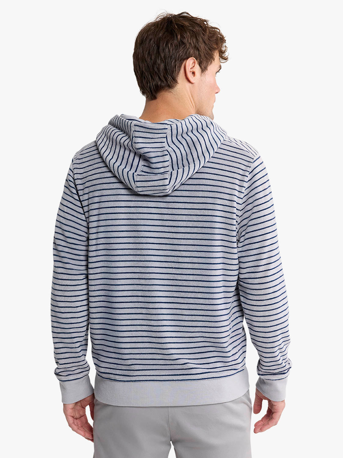 Man wearing a navy and white striped terry hoodie with ribbed cuffs, shown from behind.