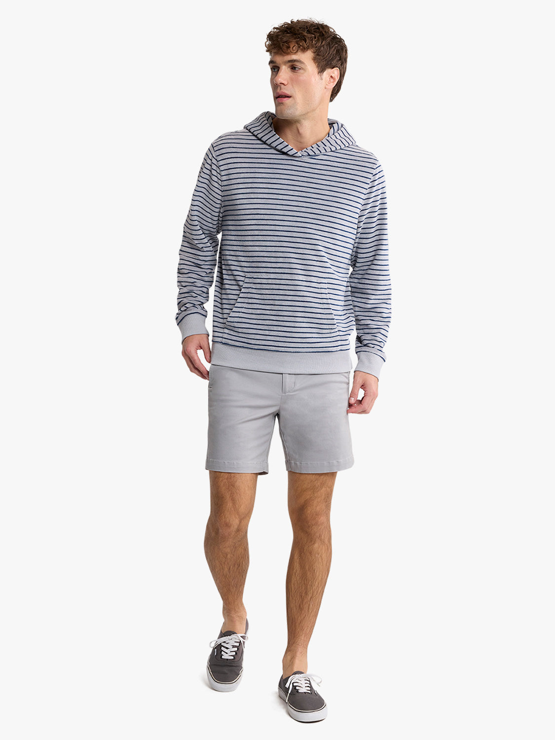 Man wearing a navy and white horizontally striped hoodie with gray shorts and black sneakers.