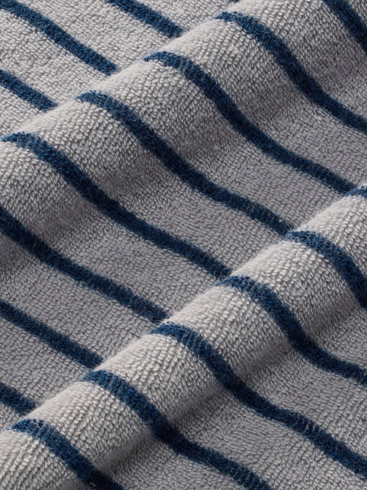 Close-up of textured terry fabric with navy blue and gray diagonal stripes.